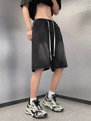 Black denim shorts with drawstring waist and diagonal seam detail.