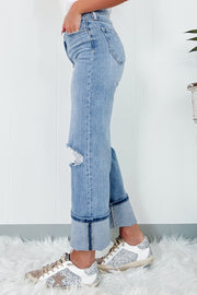 Medium wash denim jeans with distressed knee and cuffed hem