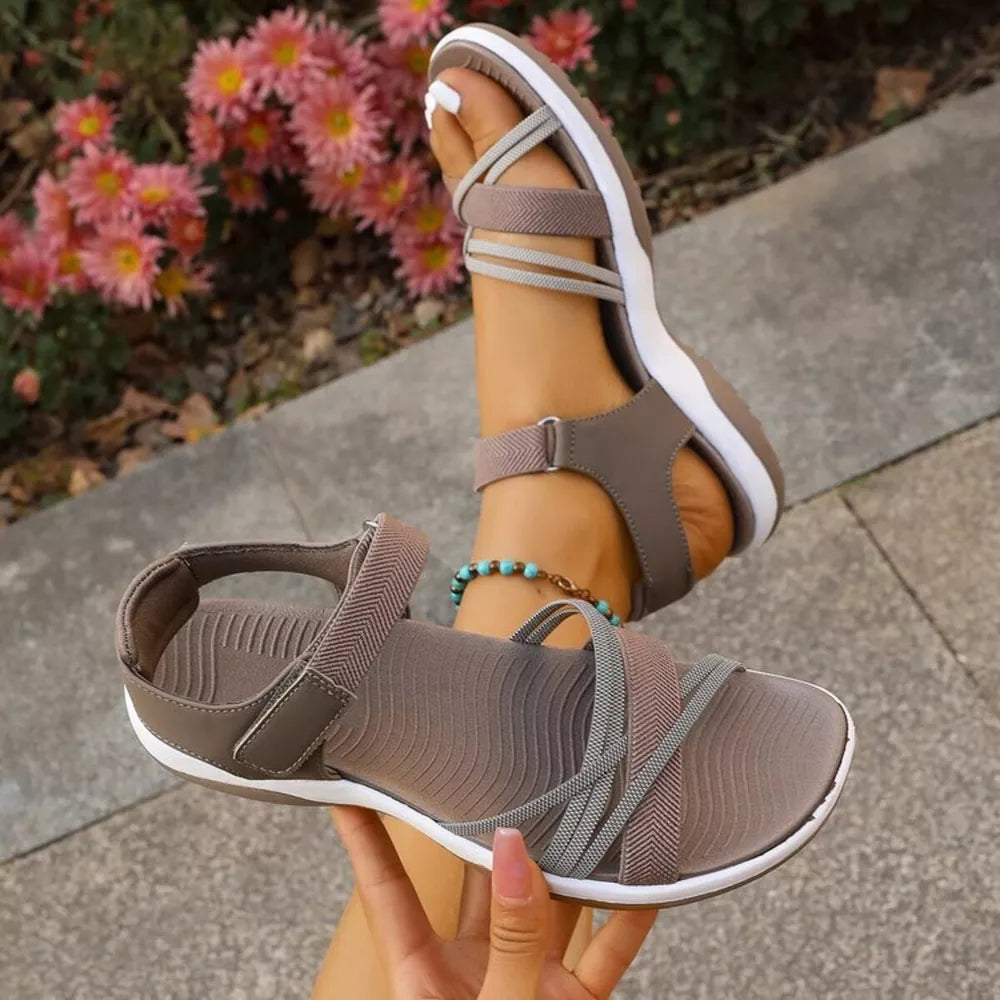 Khaki adjustable open-toe sandals with criss-cross straps and white soles.