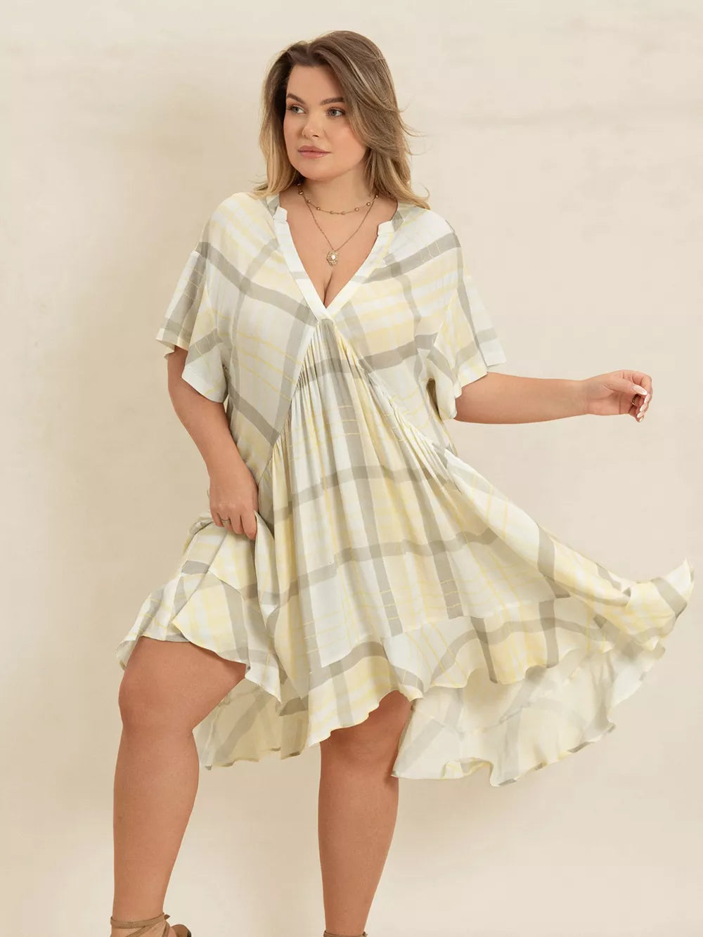 Plus size beige plaid flutter sleeve dress with V-neck and asymmetrical hem.