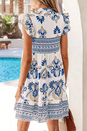 White mini dress with blue floral print, ruffled sleeves, and smocked waist detail.