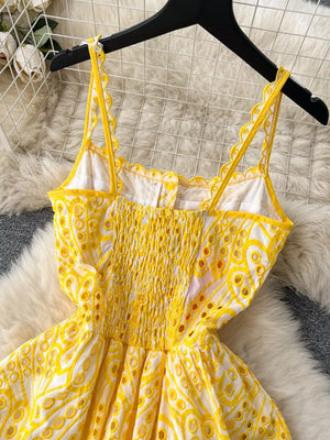 Yellow lace-embroidered cami dress with smocked bodice and tiered skirt.