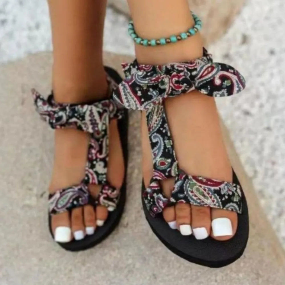 Bow-tie platform sandals in black paisley print with ankle ties and a turquoise beaded anklet.
