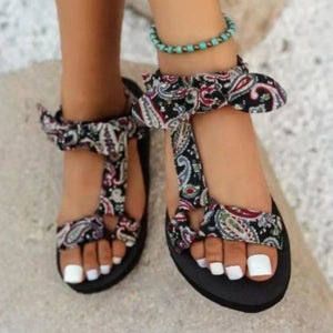 Bow-tie platform sandals in black paisley print with ankle ties and a turquoise beaded anklet.