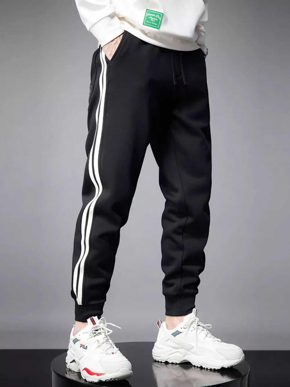 Black cotton joggers with white side stripes and cuffed ankles.