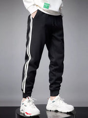 Black cotton joggers with white side stripes and cuffed ankles.