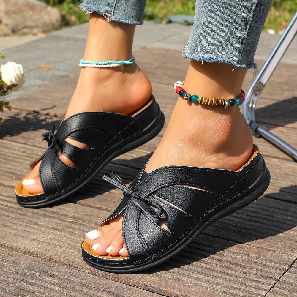 Black criss-cross wedge sandals with bow detail and open toe.