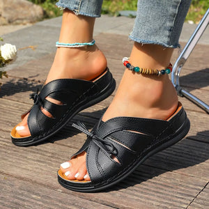 Black criss-cross wedge sandals with bow detail and open toe.