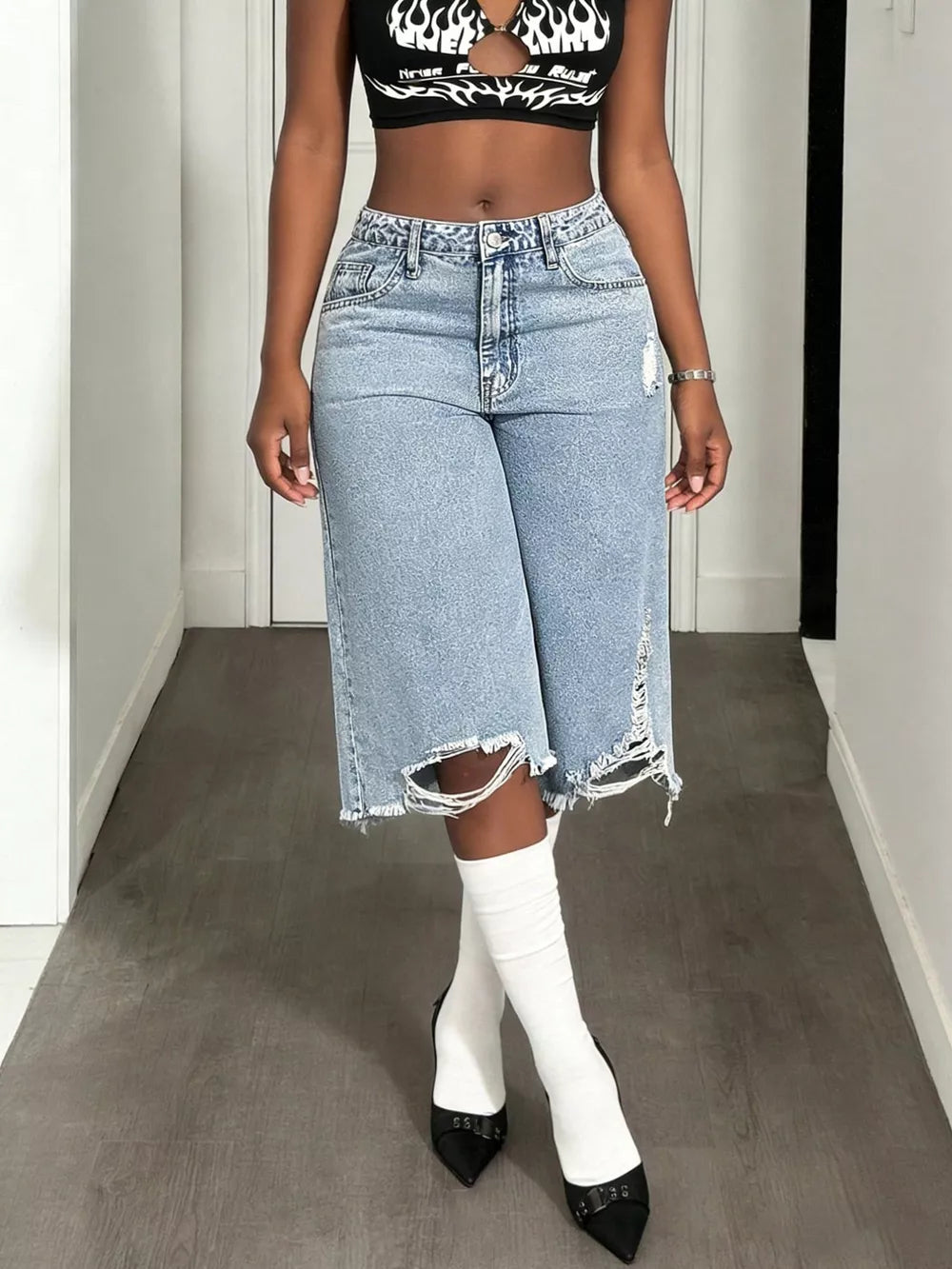 Distressed light wash denim wide-leg shorts with raw, ripped hems and pockets.