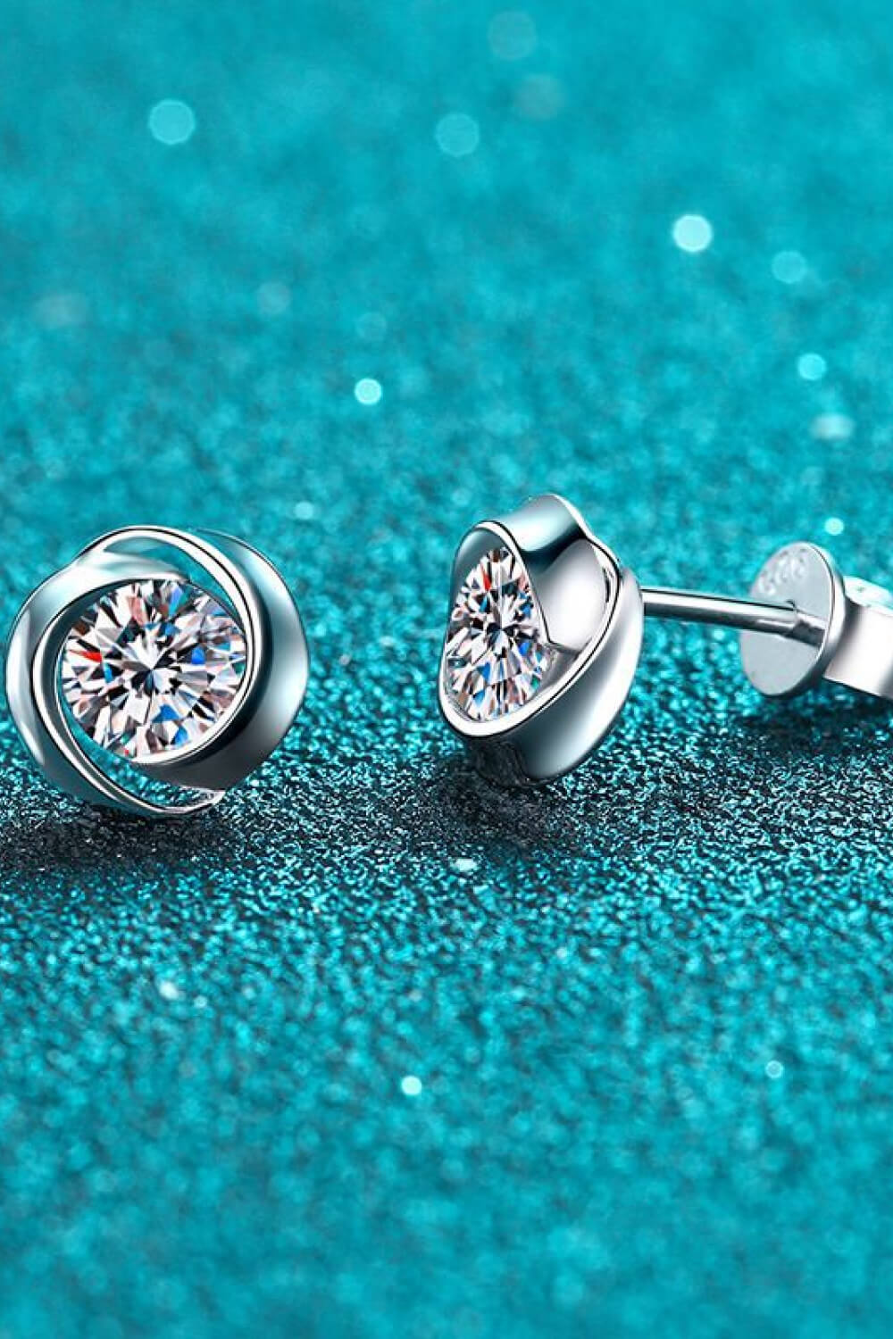 Silver halo crystal stud earrings with a swirling design.
