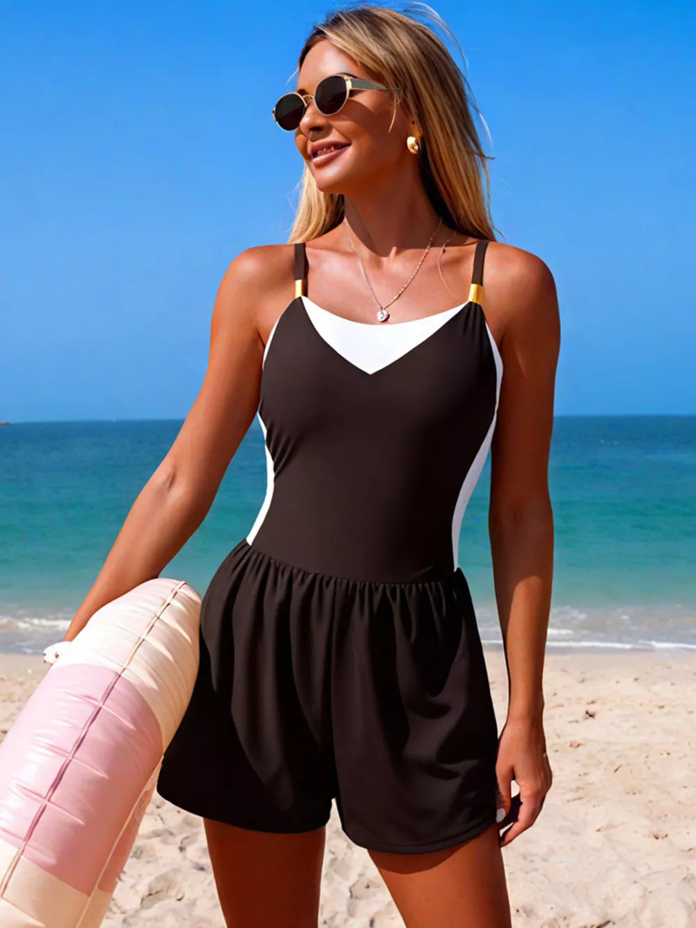 Chic color block one-piece swimsuit with black, white, and gold accents, featuring a V-neck and skirted shorts.