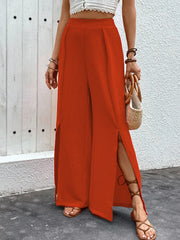 Orange-red textured palazzo trousers with dramatic side slits and wide legs.