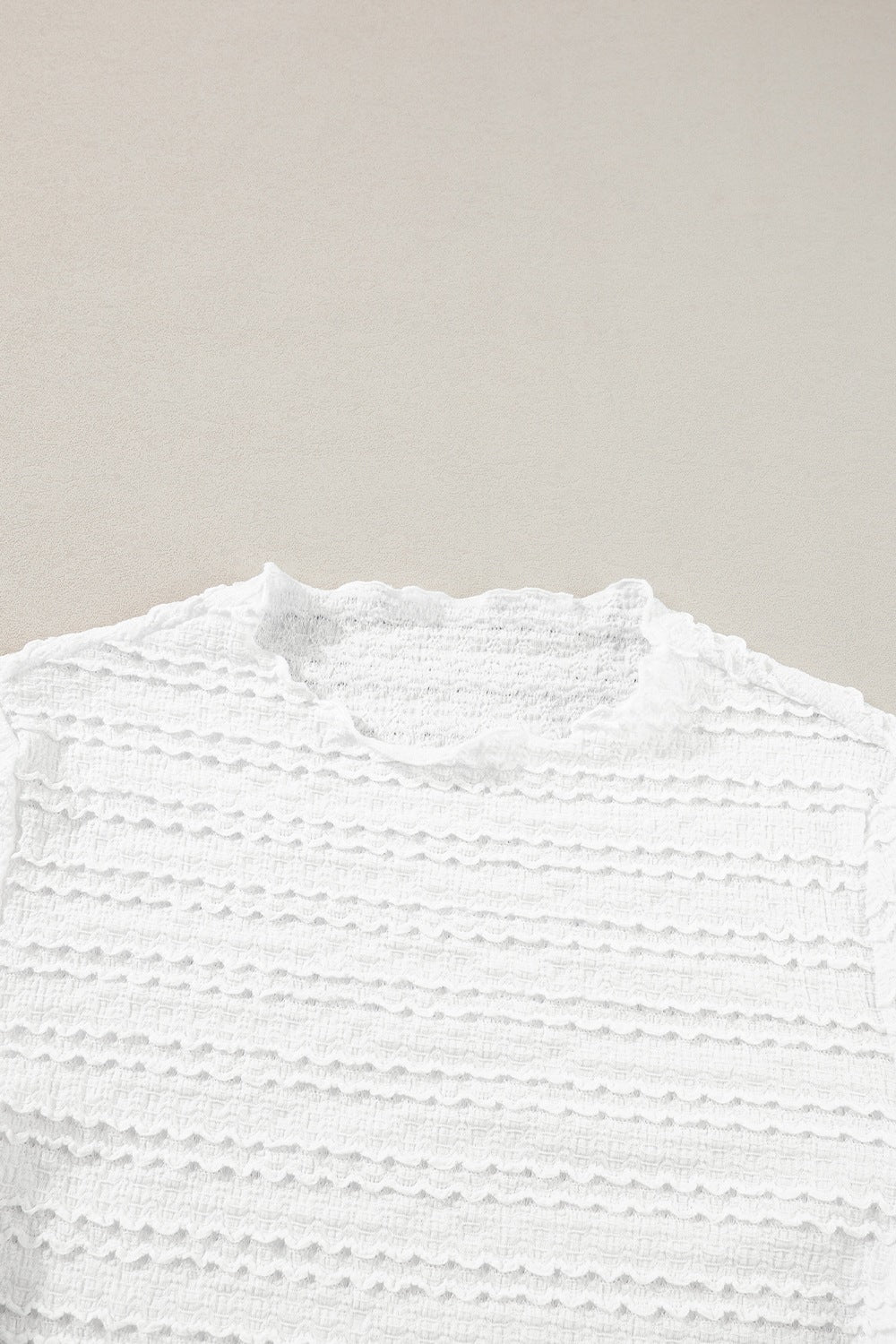 White textured long sleeve top with ruffle trim neckline and smocked fabric detail
