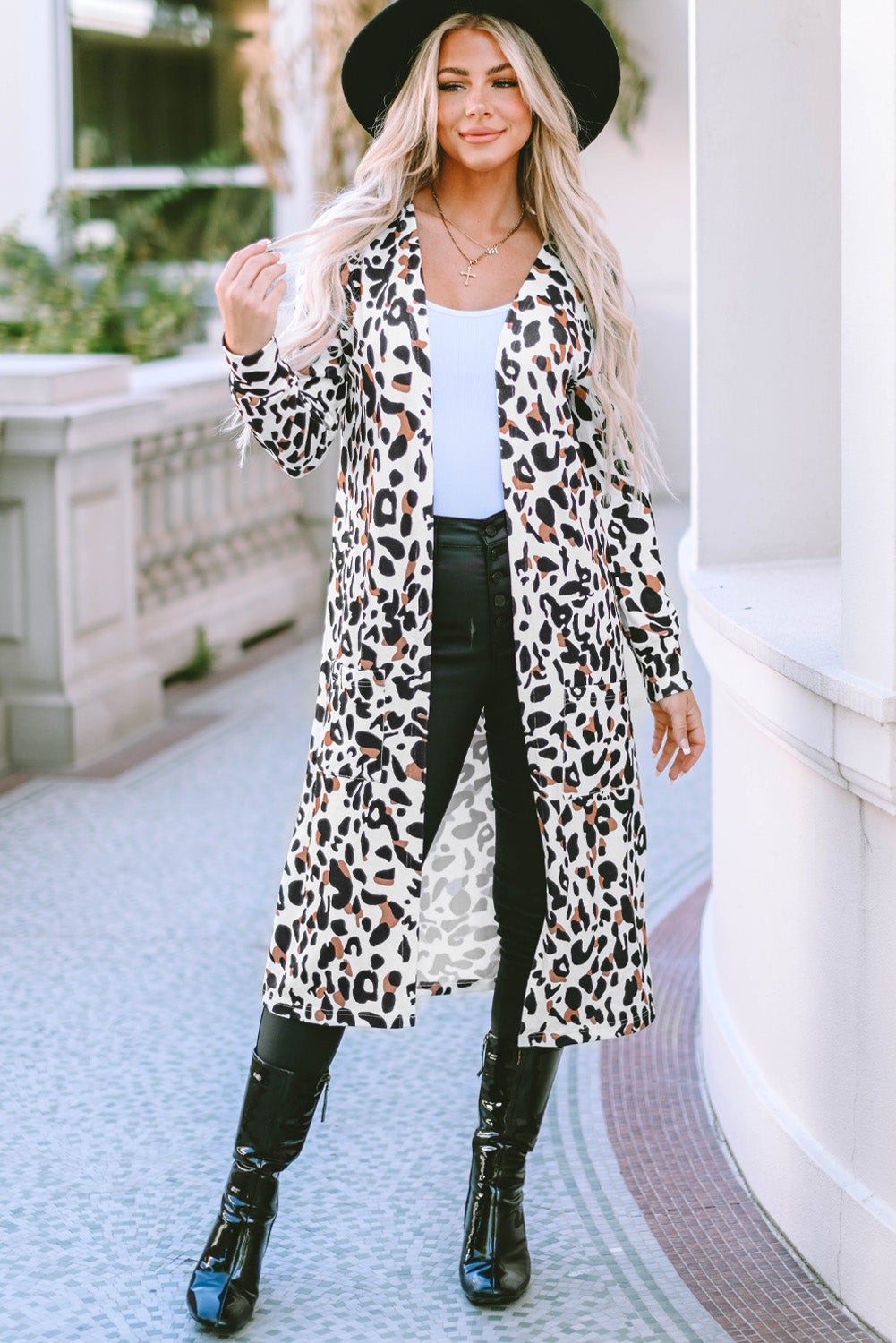 Leopard print duster cardigan with pockets and long sleeves, styled open over a white top and black pants.