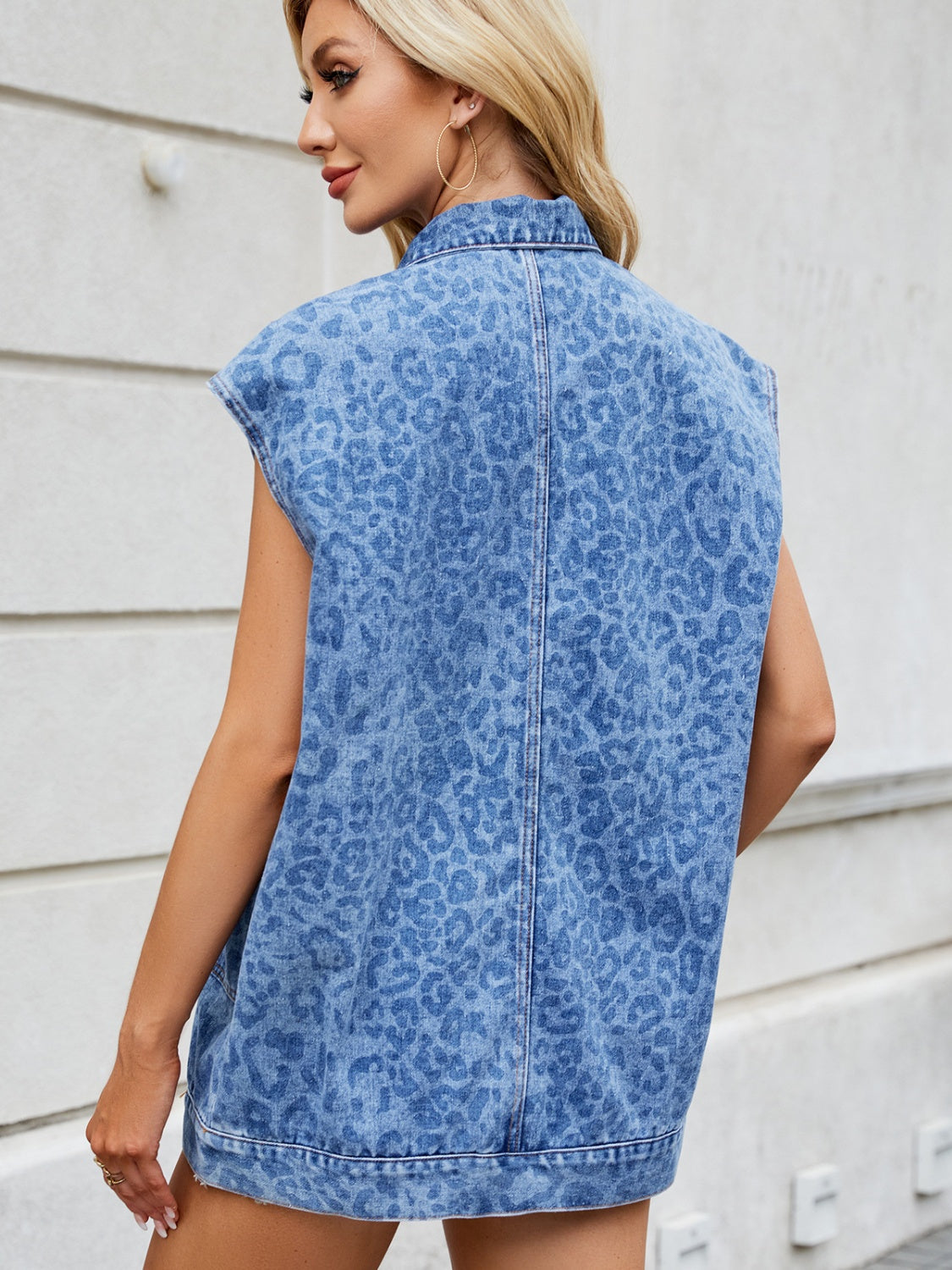 Denim leopard print sleeveless shacket in medium wash with a collar.