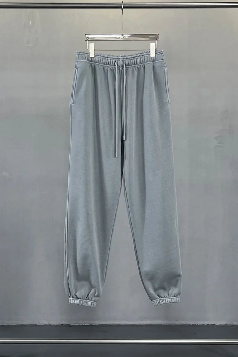 Gray relaxed fit drawstring sweatpants with elastic cuffs and side pockets.