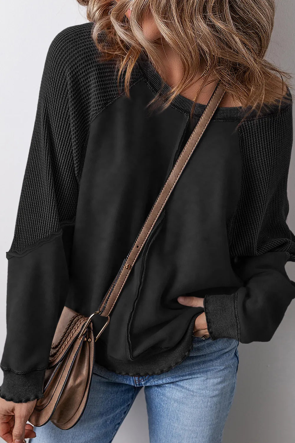 Black waffle knit raglan seam sweatshirt with raw hem detail.