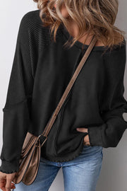 Black waffle knit raglan seam sweatshirt with raw hem detail.