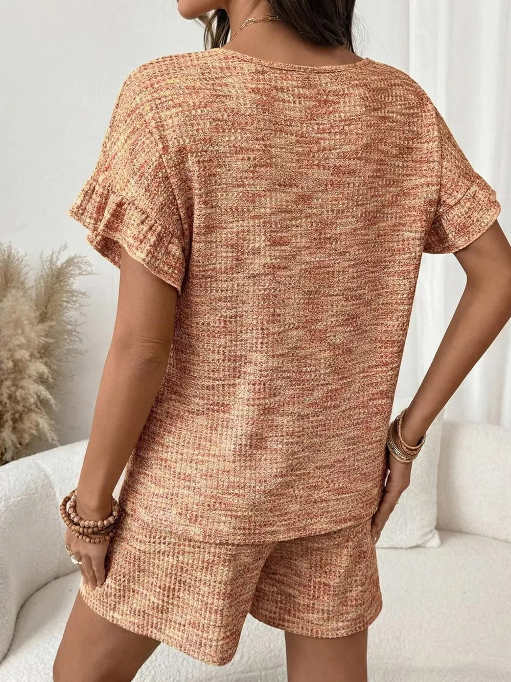 Orange-red ruffled sleeve two-piece set with textured fabric and drawstring shorts.