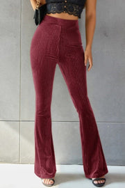 Burgundy ribbed velvet palazzo trousers with a high waist and flared leg.