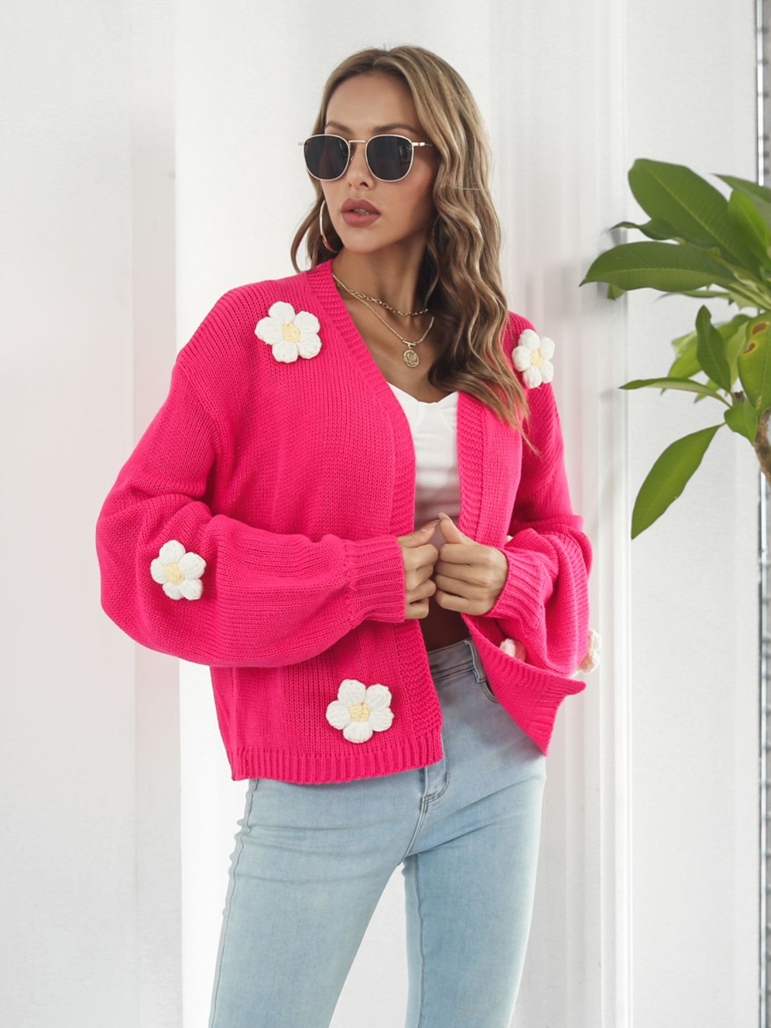 Hot pink knit cardigan with floral appliqués and balloon sleeves.