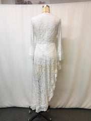 White lace asymmetrical V-neck dress with bell sleeves and ruffled hem.