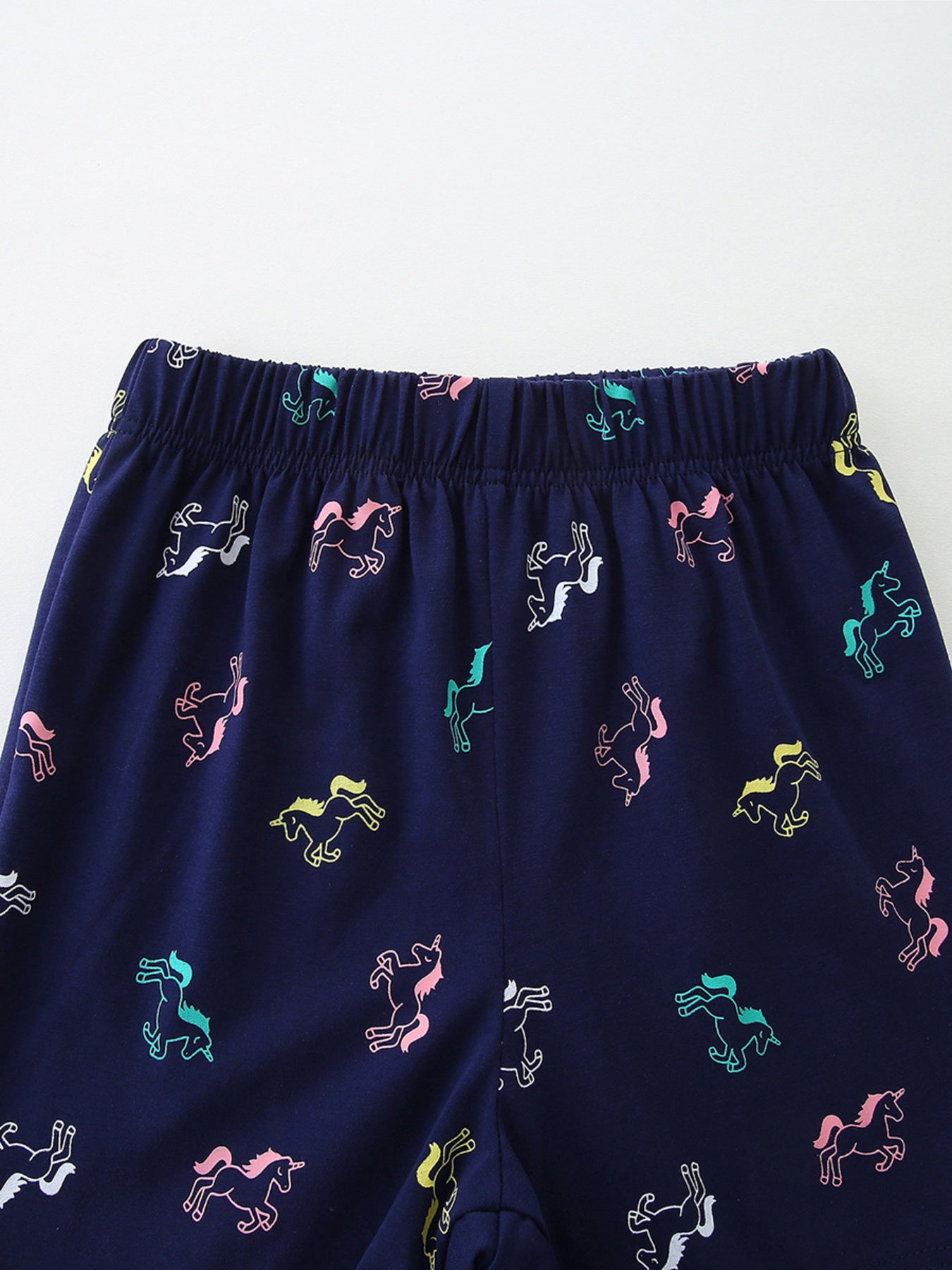 Navy cotton toddler sleepwear pants with colorful unicorn print and elastic waistband.