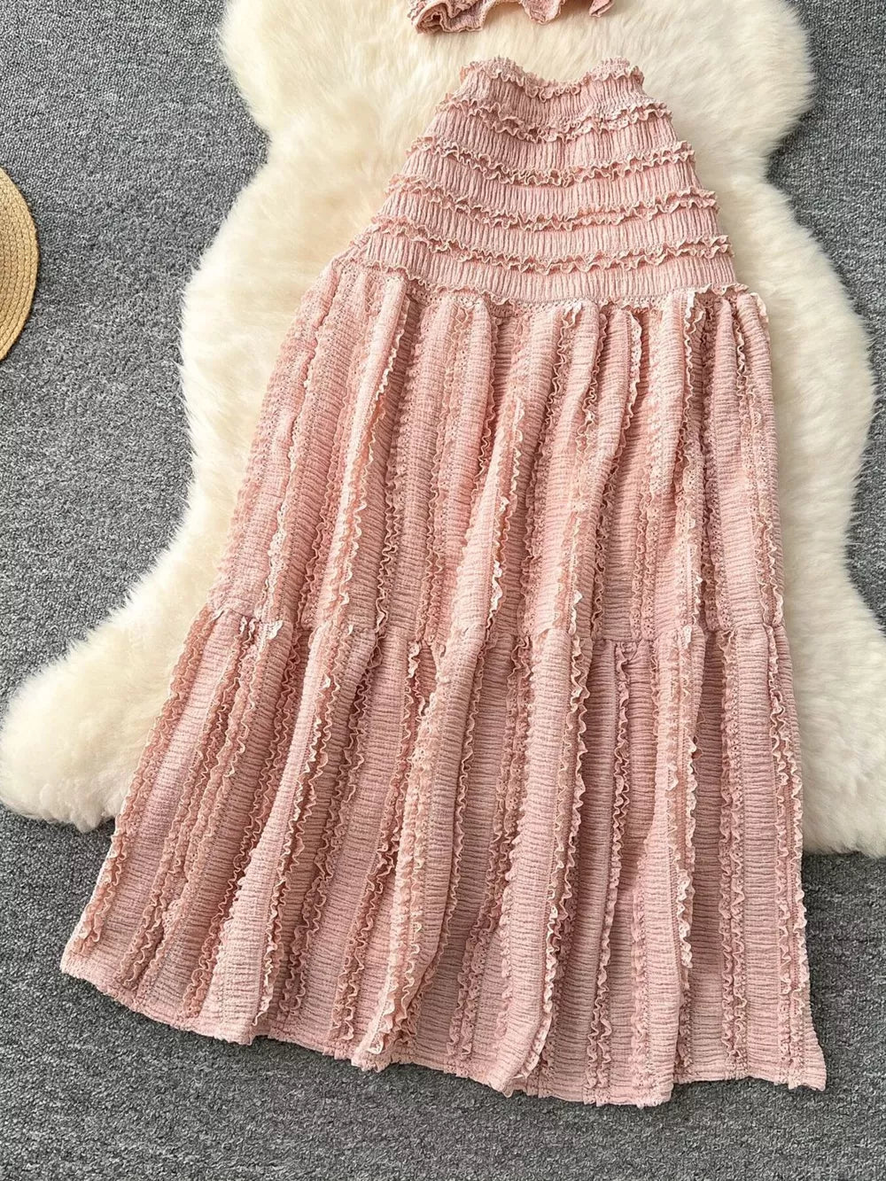 Pink textured two-piece set with smocked top and ruffled tiered skirt.