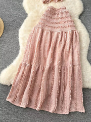 Pink textured two-piece set with smocked top and ruffled tiered skirt.