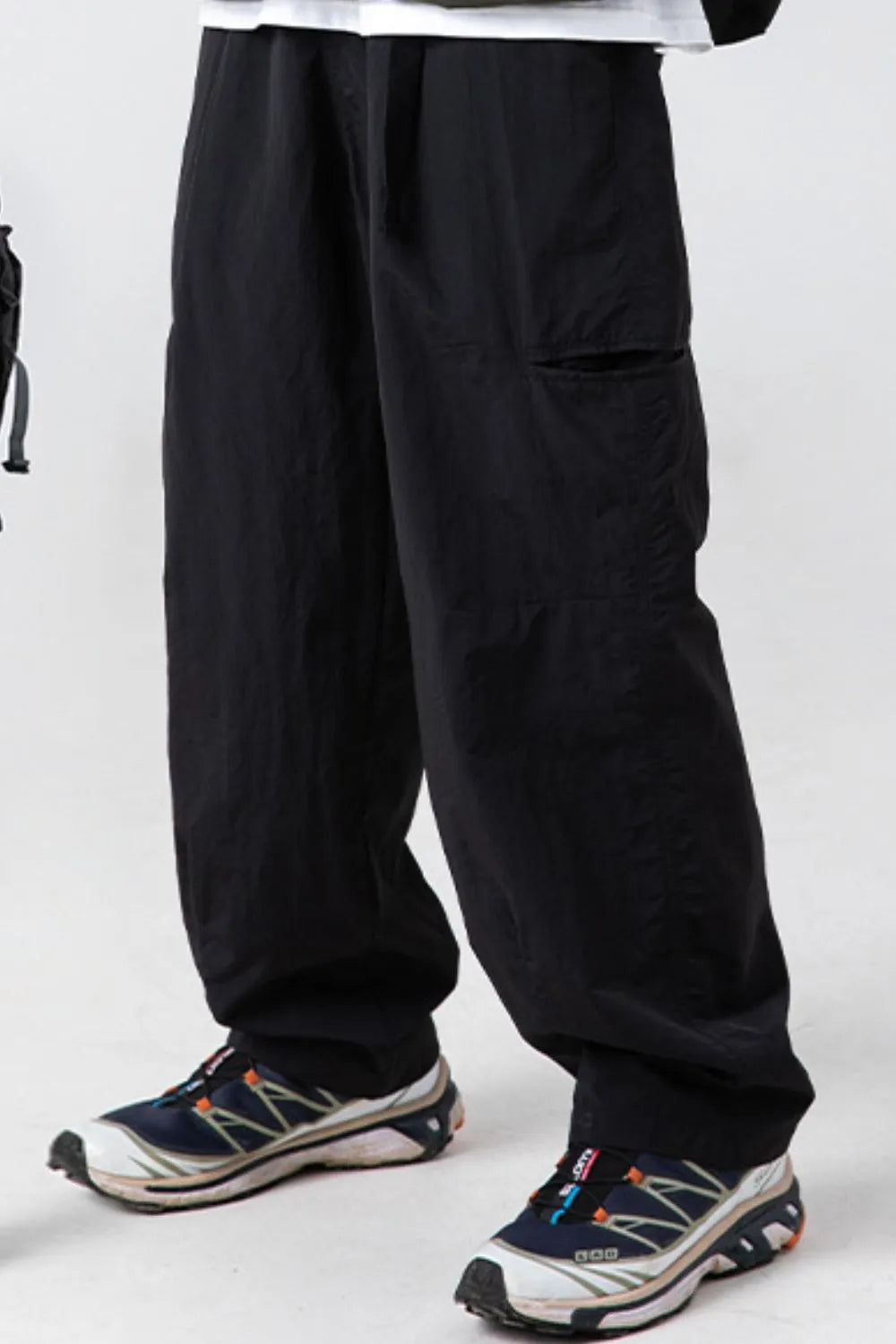 Black technical fabric cargo pants with multiple pockets and a relaxed fit.