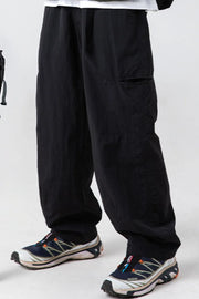 Black technical fabric cargo pants with multiple pockets and a relaxed fit.
