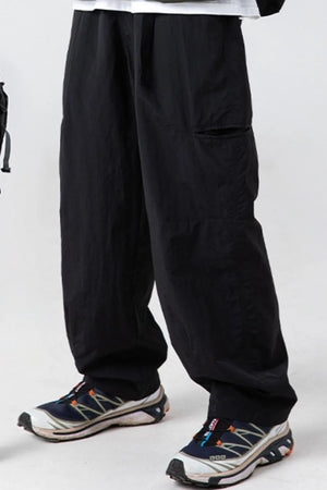 Black technical fabric cargo pants with multiple pockets and a relaxed fit.