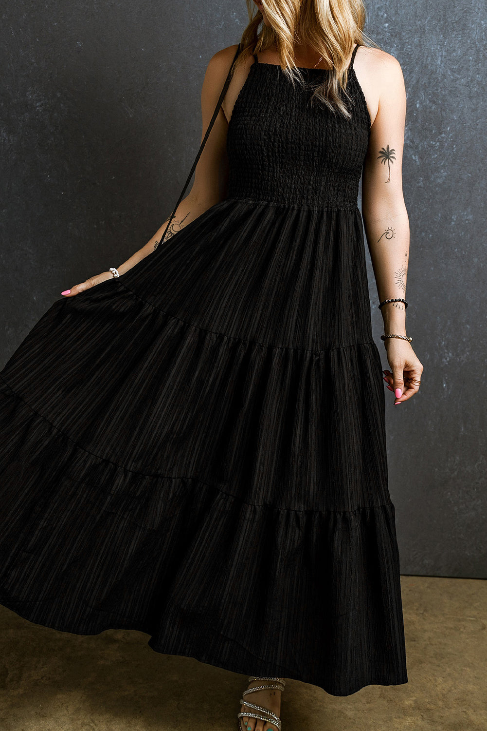 Black tiered maxi dress with textured smocked bodice and subtle vertical stripes.