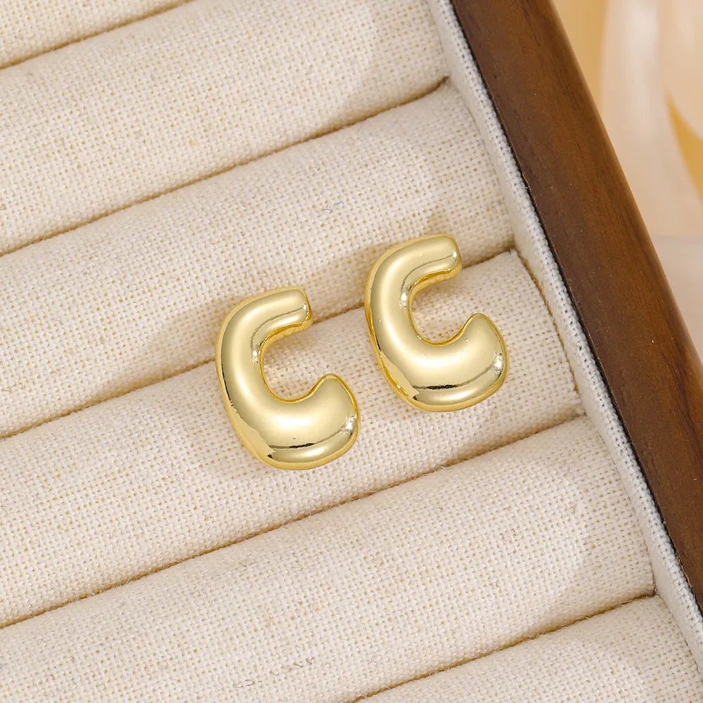 Gold sculptural stud earrings in the shape of the letter C