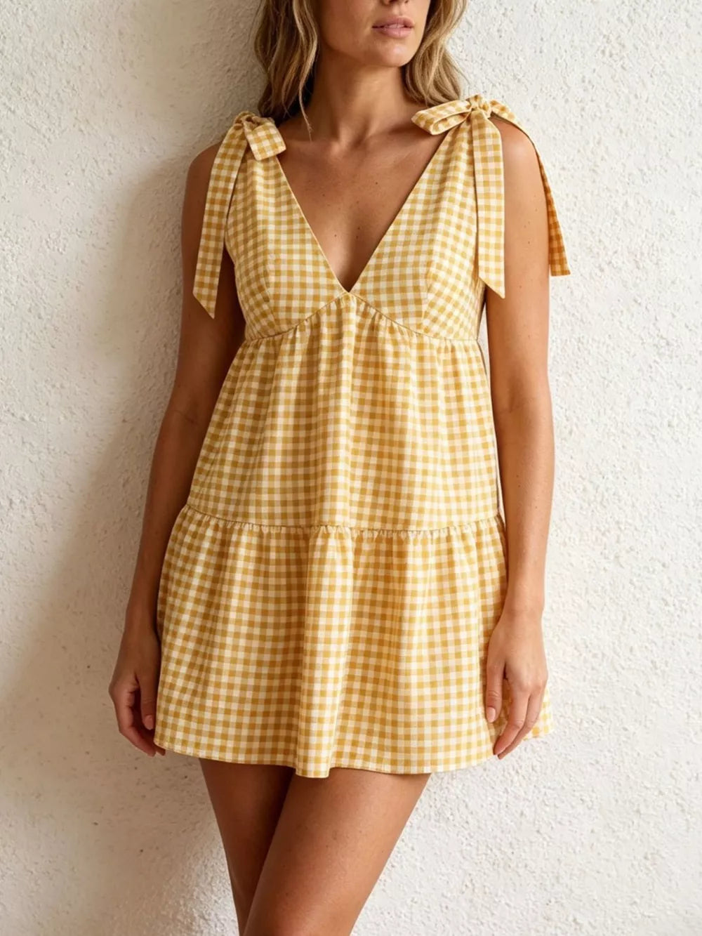 Yellow gingham mini dress with tie straps and tiered skirt.