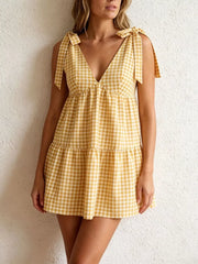 Yellow gingham mini dress with tie straps and tiered skirt.