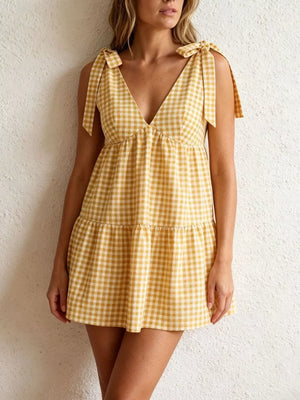 Yellow gingham mini dress with tie straps and tiered skirt.