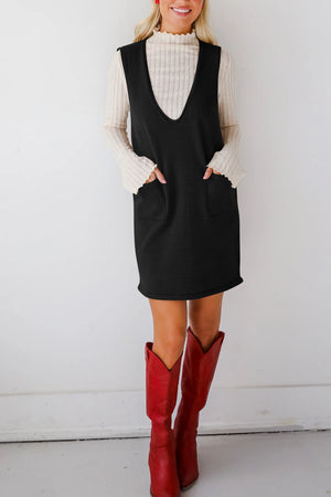 Black V-neck sweater dress with pockets, styled with a cream ribbed top and red boots.