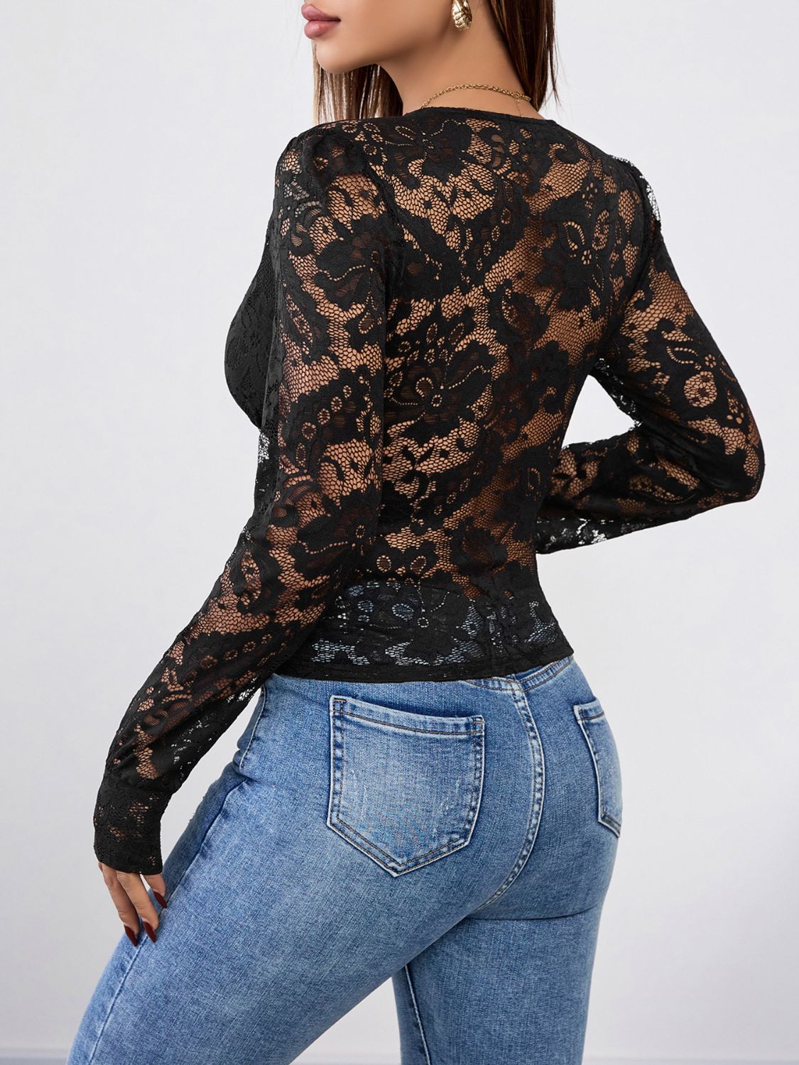 Black lace wrap bodysuit with long sleeves and scalloped trim, styled with jeans.