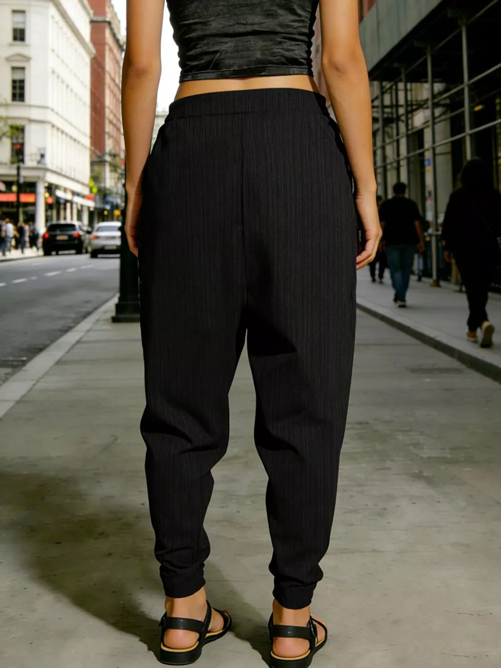 Black pinstripe harem pants with cuffed ankles and decorative button detail.