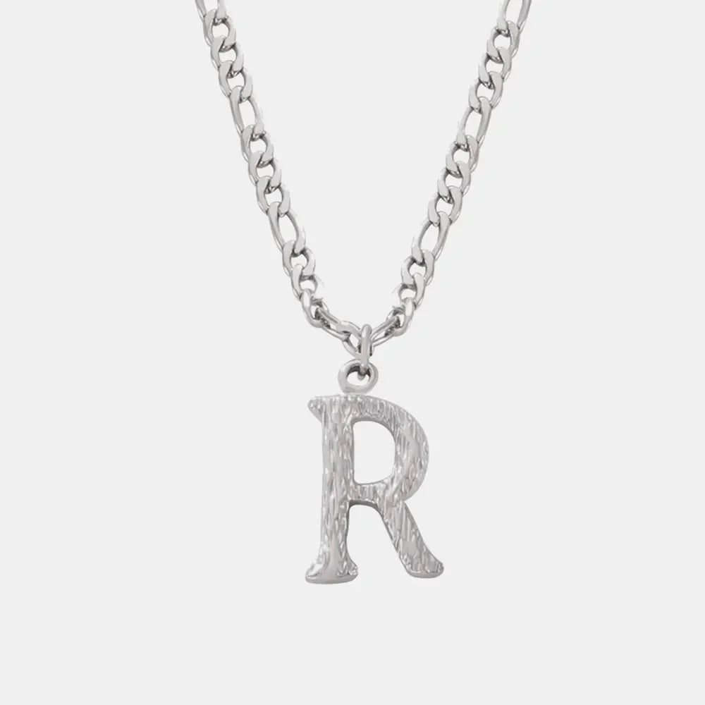 Textured initial pendant necklace with a silver chain and an R charm.
