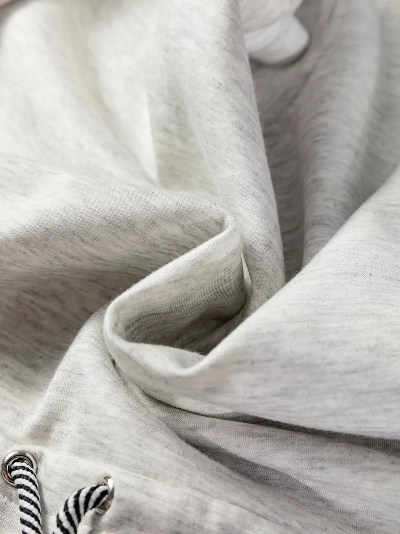Light gray drawstring waist tunic sweatshirt detail with black and white striped drawstrings.