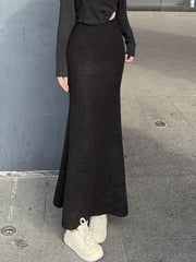 Black textured knit mermaid maxi skirt with a flared hem, styled with white sneakers.