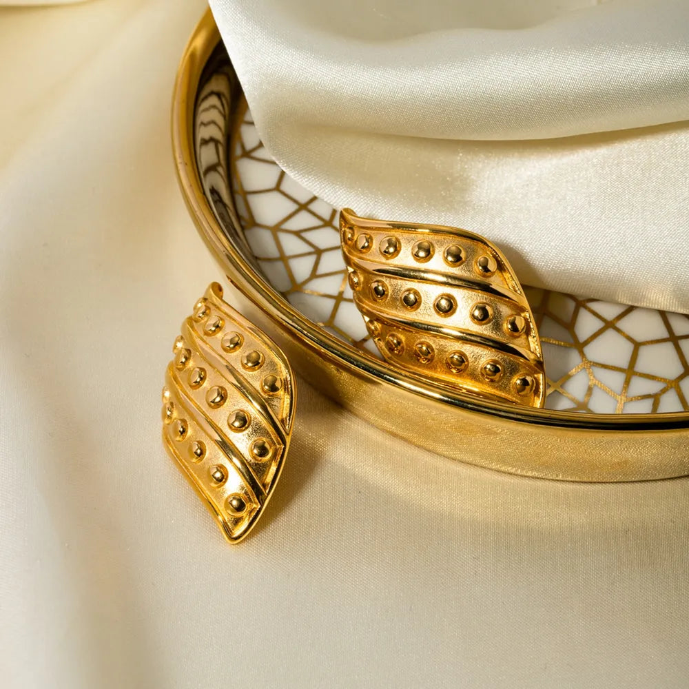 Sculpted gold leaf stud earrings with raised dot details, 18K gold-plated.