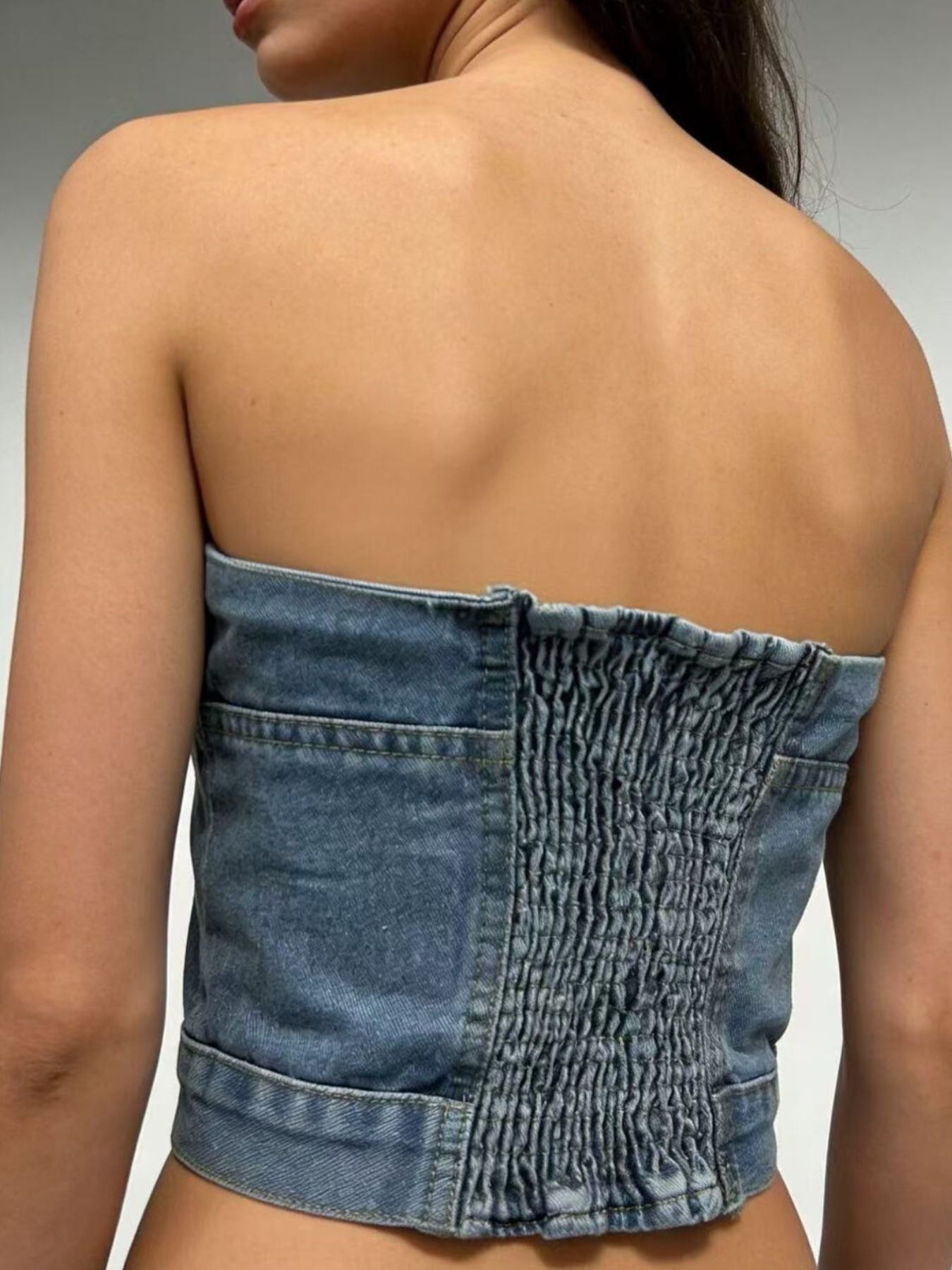 Structured denim tube top with smocked back detail and button accents, casual chic style.