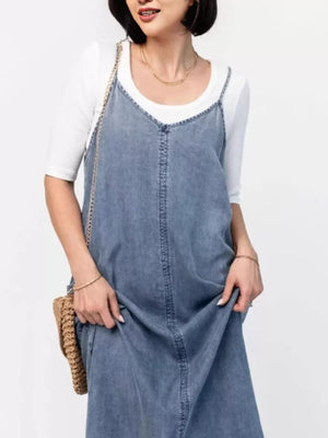 Light blue washed denim maxi dress with V-neck and spaghetti straps, styled with a white tee.