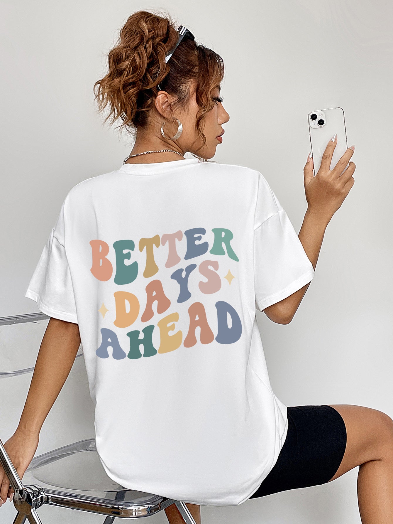 White oversized graphic tee with retro "Better Days Ahead" text in pastel colors.