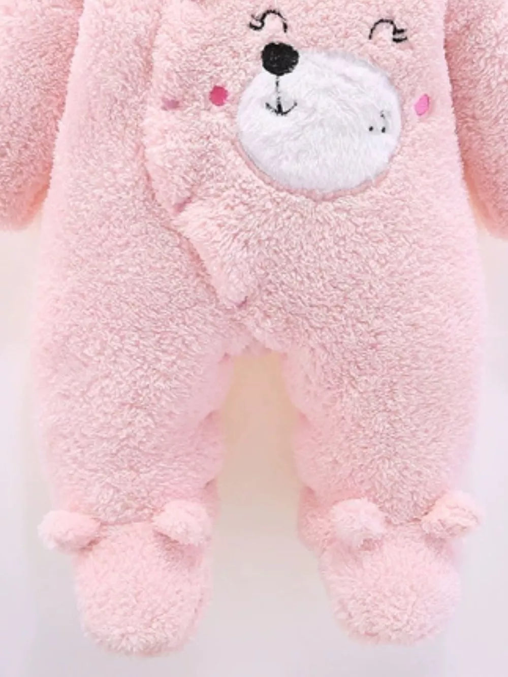 Blush pink plush baby one-piece with bear ears hood and footie details.