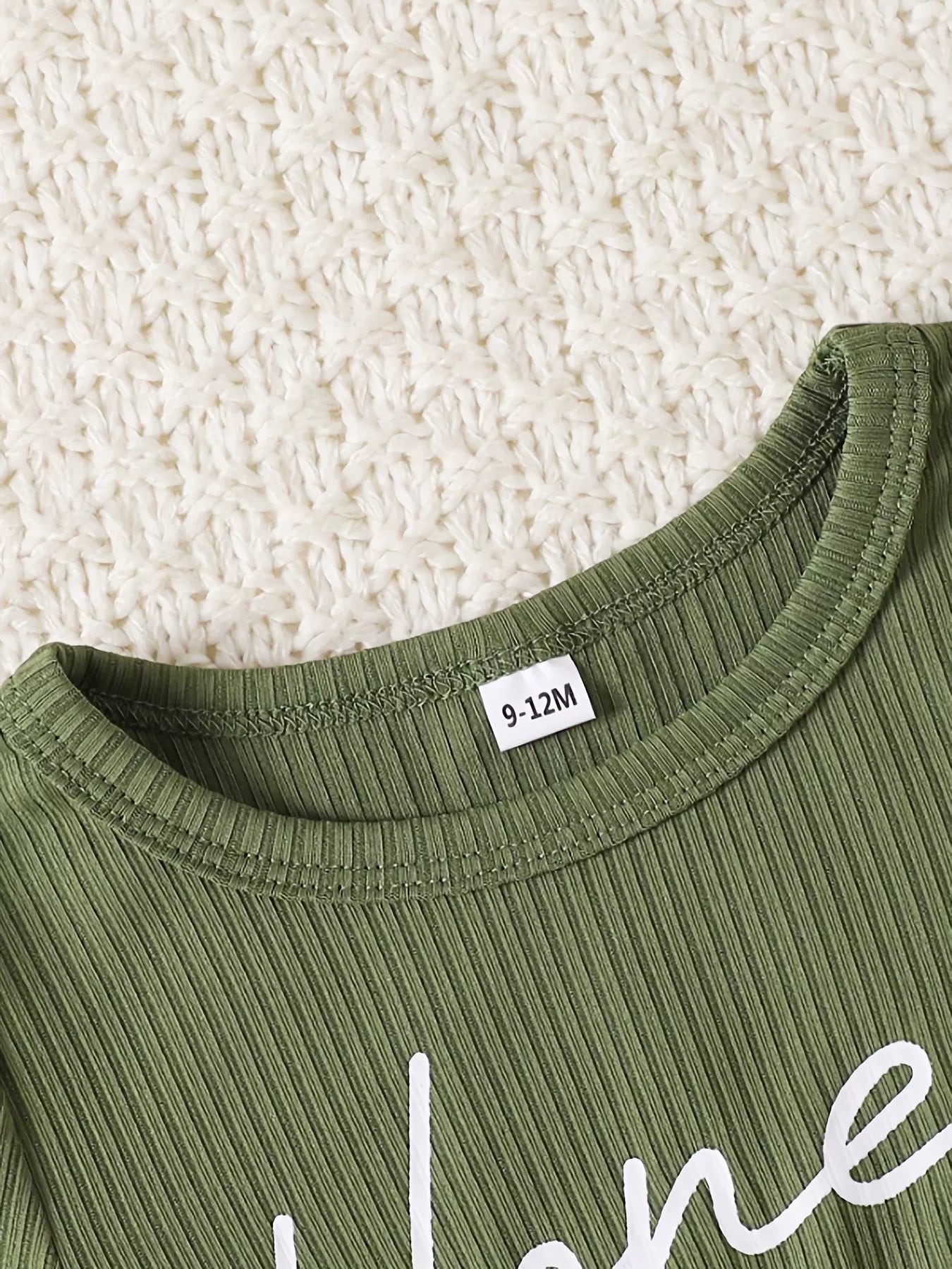 Green ribbed baby set with white script text and a size tag.