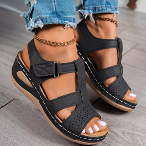 Black perforated mid-wedge sandals with adjustable straps and white stitching detail.